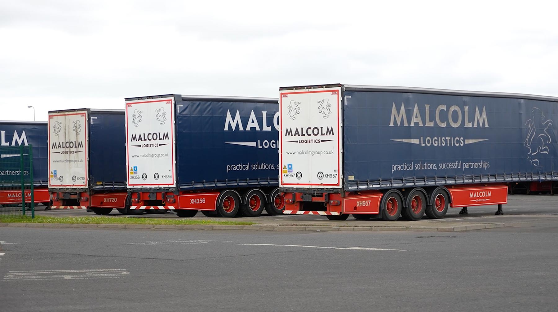A row of Malcolm Logistics trucks in a car park